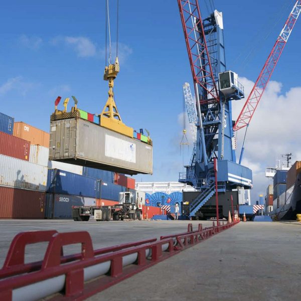 A crane detaching a container onto a truck from a ship on a port