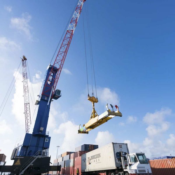 A crane detaching a container onto a truck from a ship on a port